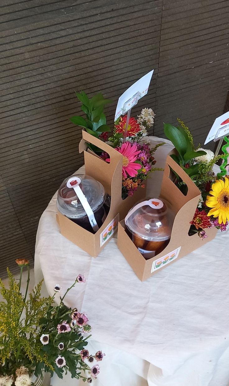 two boxes filled with drinks sitting on top of a table covered in flowers and greenery