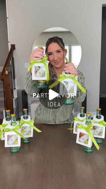 a woman is holding up some bottles on the table