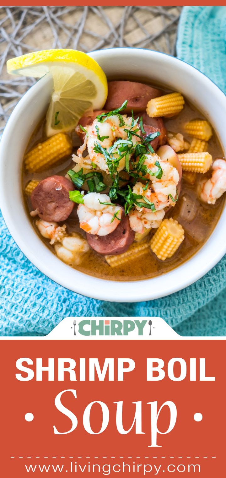 shrimp boil soup in a white bowl with corn on the cob and garnish