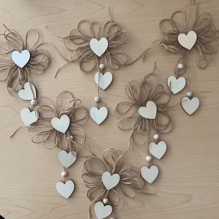 several white hearts and bows are hanging on a wooden table with string attached to them