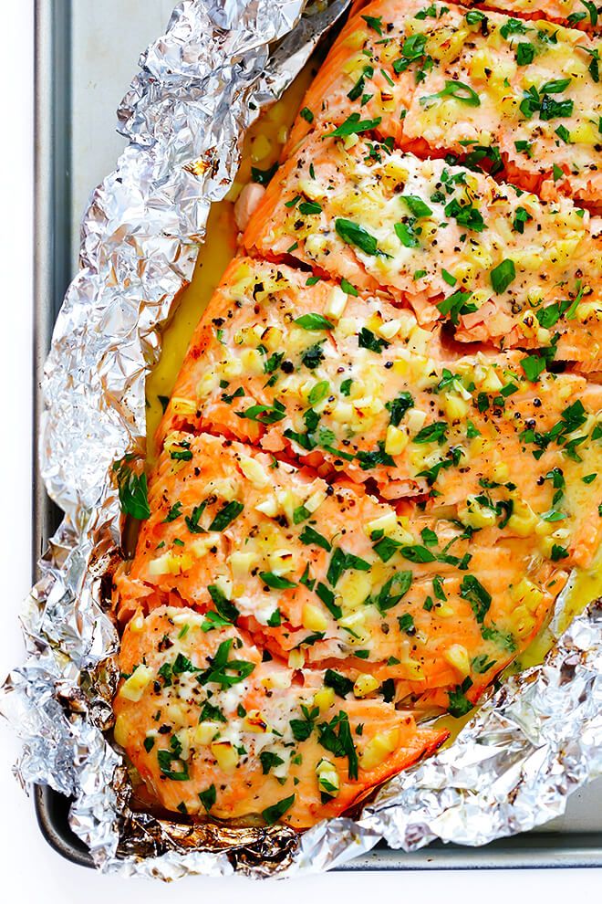 the salmon is covered in herbs and seasonings on top of tin foil, ready to be cooked