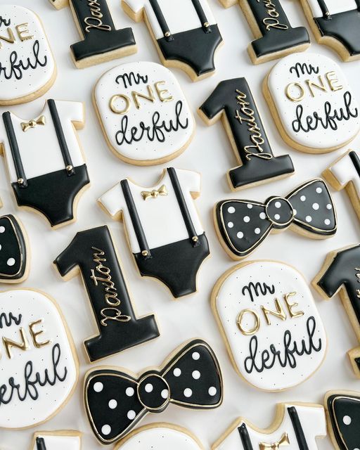 decorated cookies with black and white designs are arranged on a table for a first birthday party