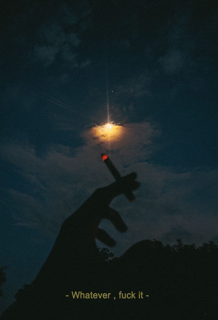 a person's hand holding a cross with the moon in the background