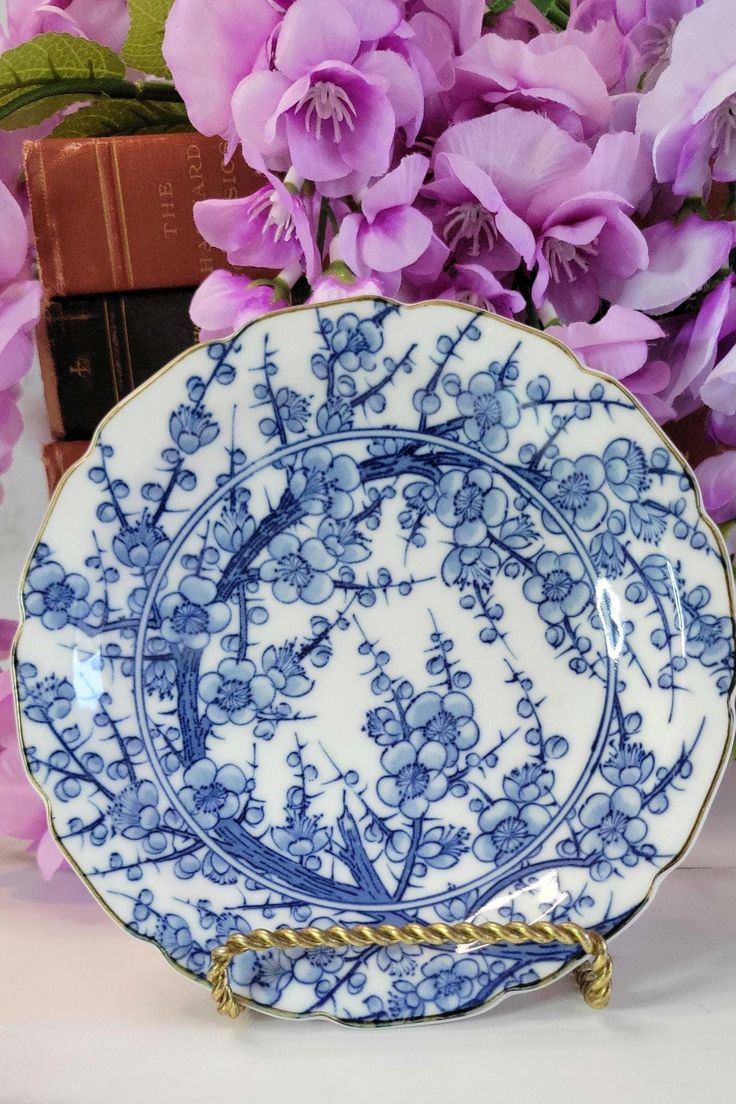 a blue and white plate sitting next to purple flowers