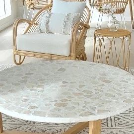 a living room with wicker furniture and white rugs on the floor in front of large windows