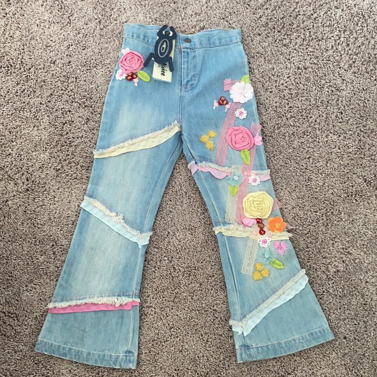 a pair of jeans with flowers on them sitting on the floor in front of carpet