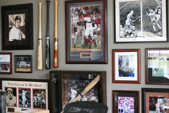 a wall with baseball memorabilia and framed pictures on it's sides, including bats