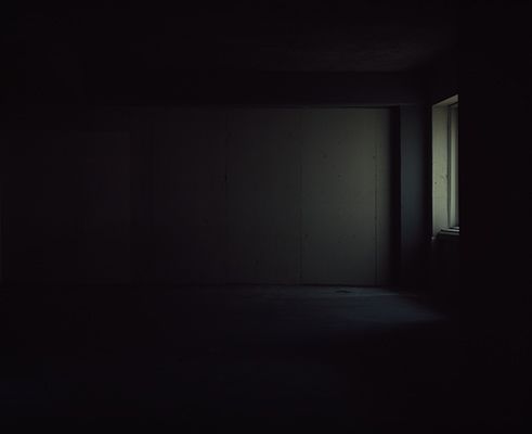 an empty room with light coming in from the window and dark lighting on the wall