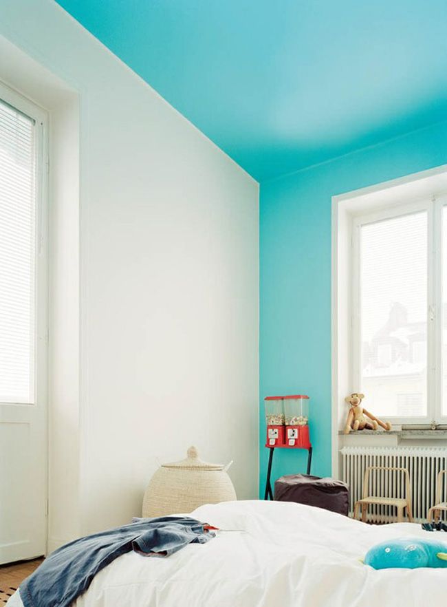 a bedroom painted in blue and white with an unmade bed on top of it