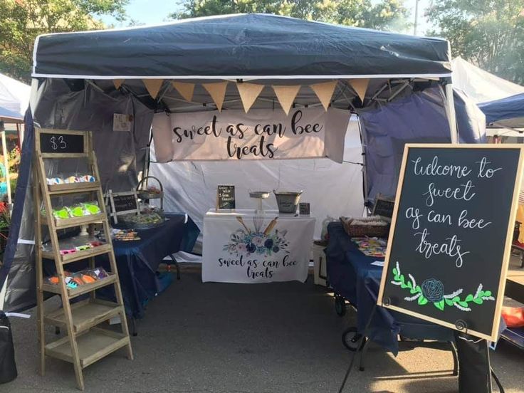 an outdoor market with tables and signs on the side of it that read sweet as can be treats