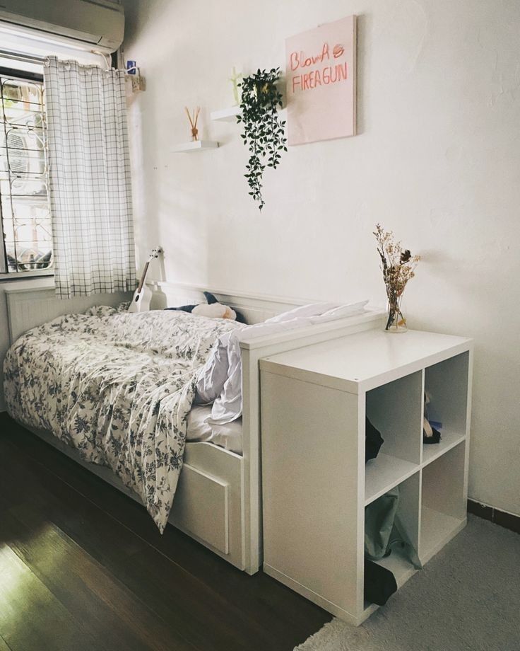 a bedroom with a bed, dresser and window in it's corner area next to a wooden floor