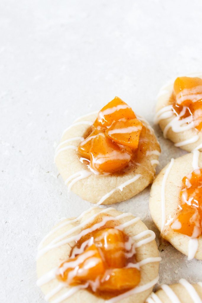 small cookies with icing and fruit on them sitting on a white counter top next to each other