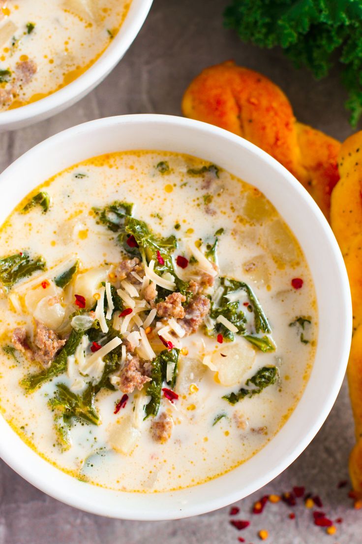 two white bowls filled with soup next to oranges