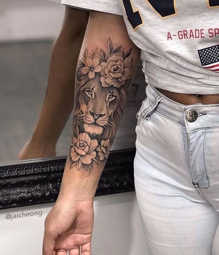 a woman's arm with a lion and flowers tattoo on her left arm, next to a mirror