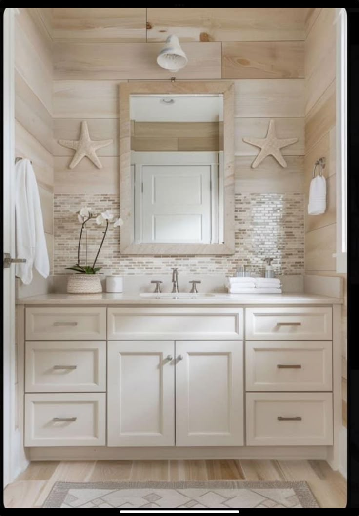 a bathroom with white cabinets and starfish on the wall