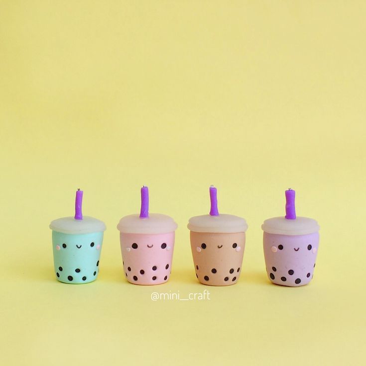 three cups with straws and polka dots are lined up against a yellow background,