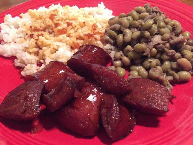 a red plate topped with meat, beans and rice