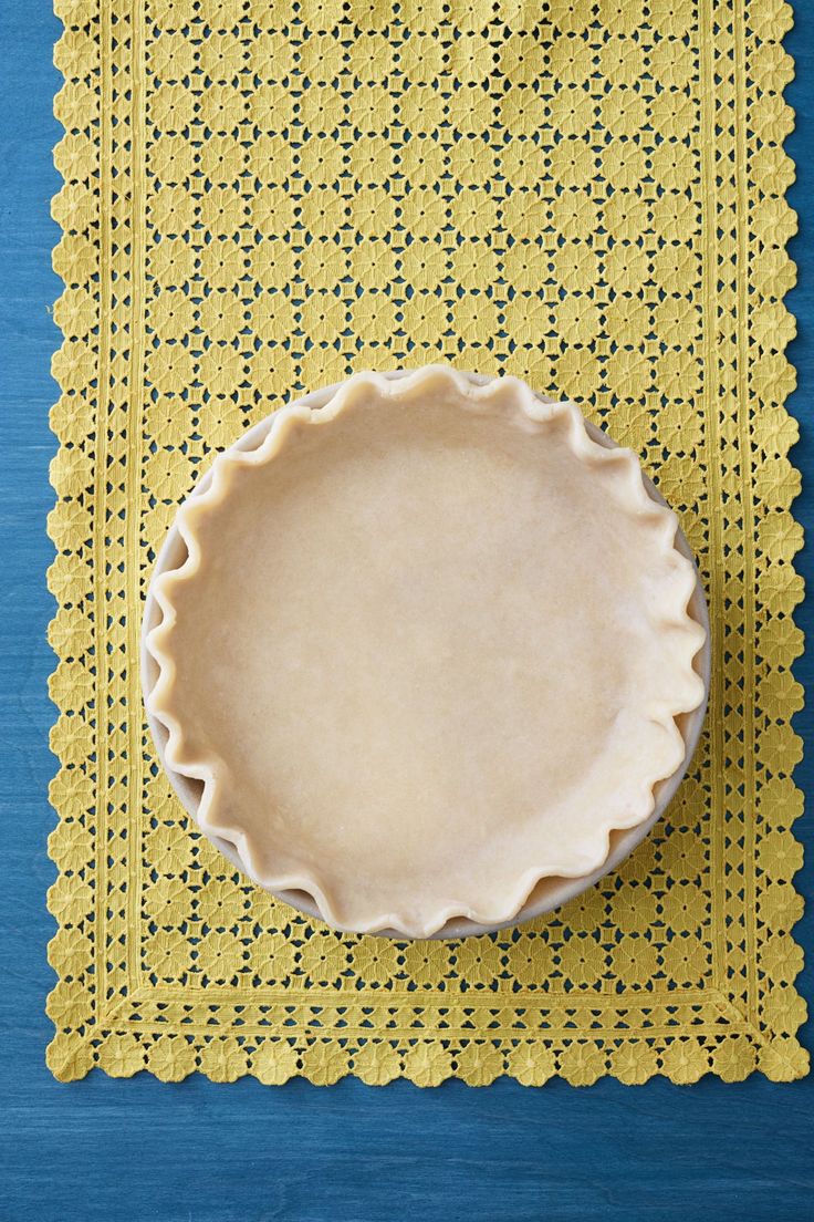 a pie crust sitting on top of a yellow placemat next to a blue table