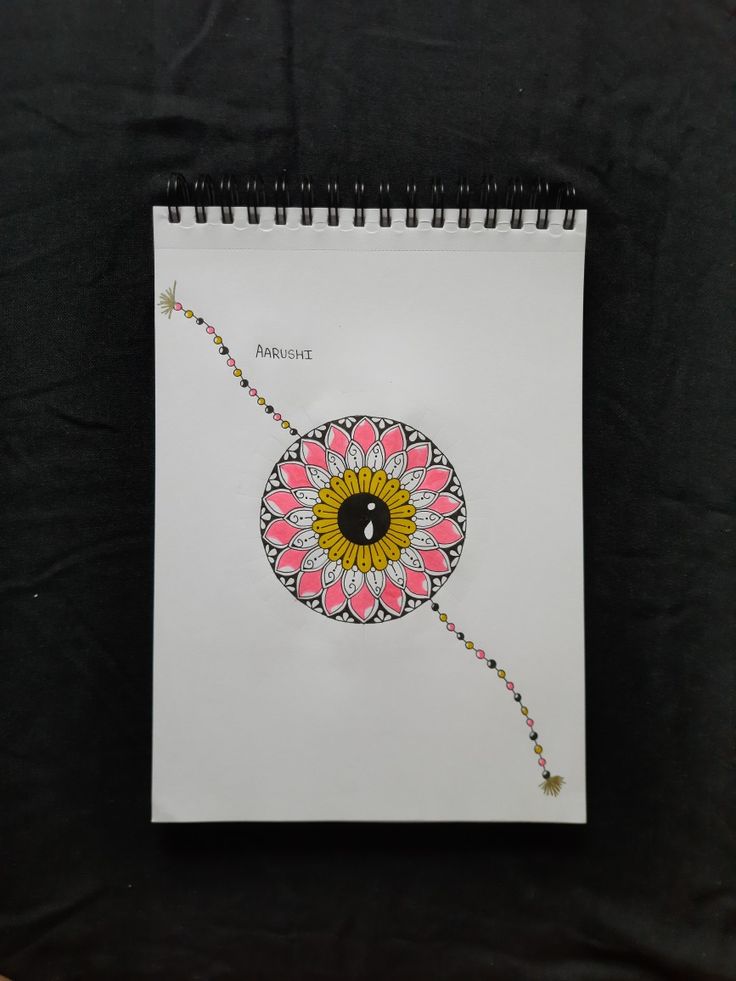 a spiral notebook with an image of a flower on the cover and beaded string attached to it