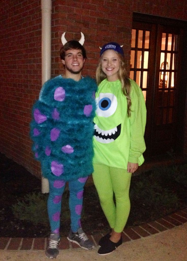 two people dressed up as monsters standing next to each other in front of a brick building