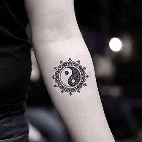 a woman's arm with a tattoo on it that has a yin symbol in the middle