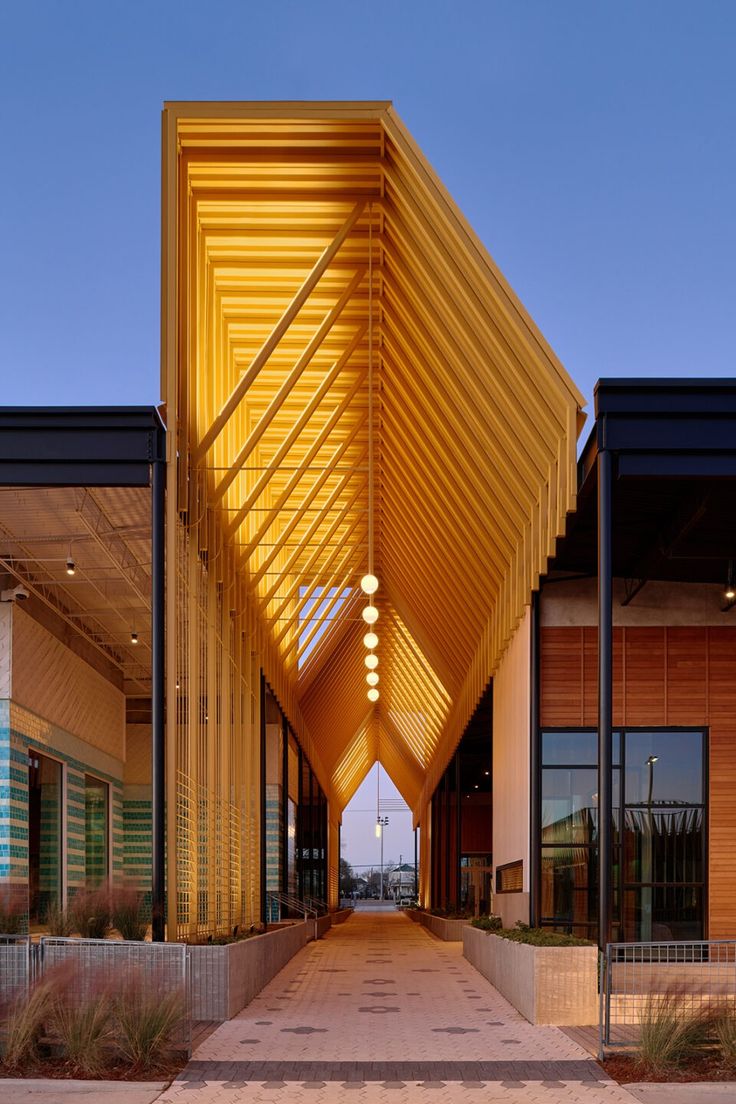 the entrance to an office building with large wooden beams on it's roof and walkway