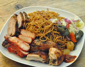 a white plate topped with meat, noodles and veggies on top of a wooden table