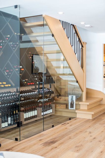 there is a wine cellar in the middle of this room with glass walls and stairs