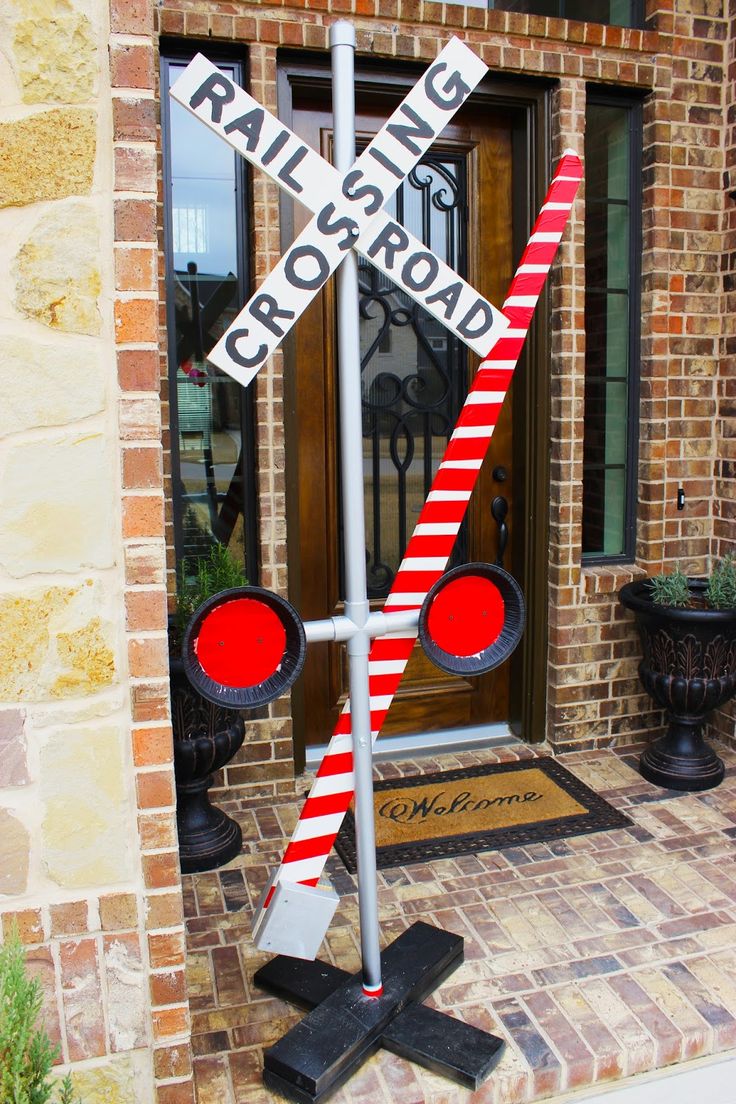 a red and white railroad crossing sign sitting in front of a brick building next to a door