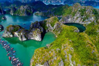 an aerial view of many boats docked in the water near mountains and cliffs with green vegetation