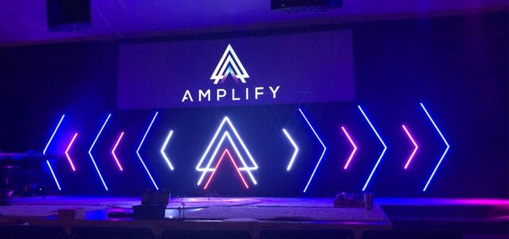 an empty stage is lit up with purple and blue lights in front of the ampley logo