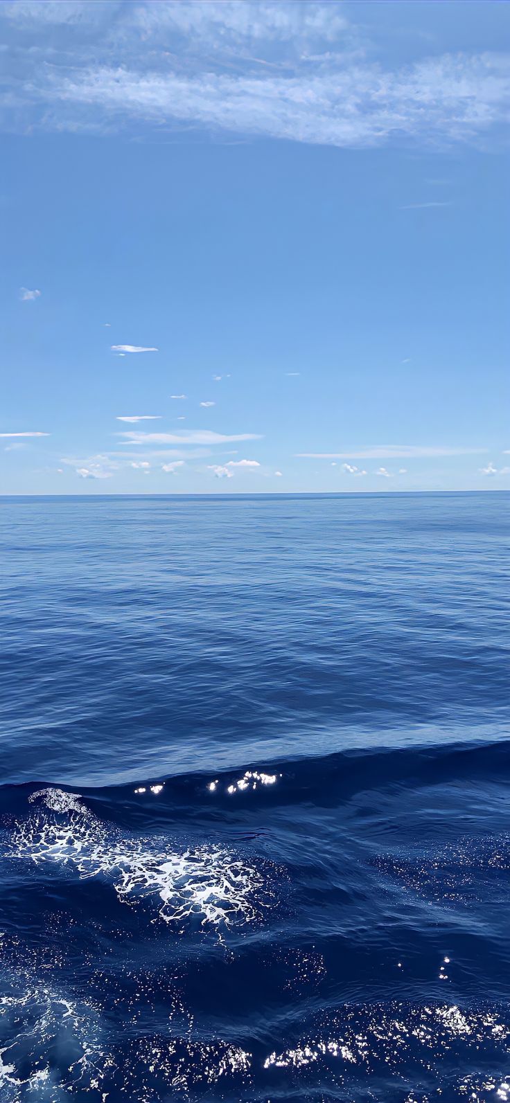 the ocean is blue and clear with some clouds