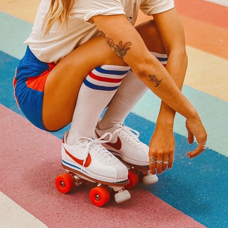 a woman sitting on top of a skateboard wearing white socks and knee high socks