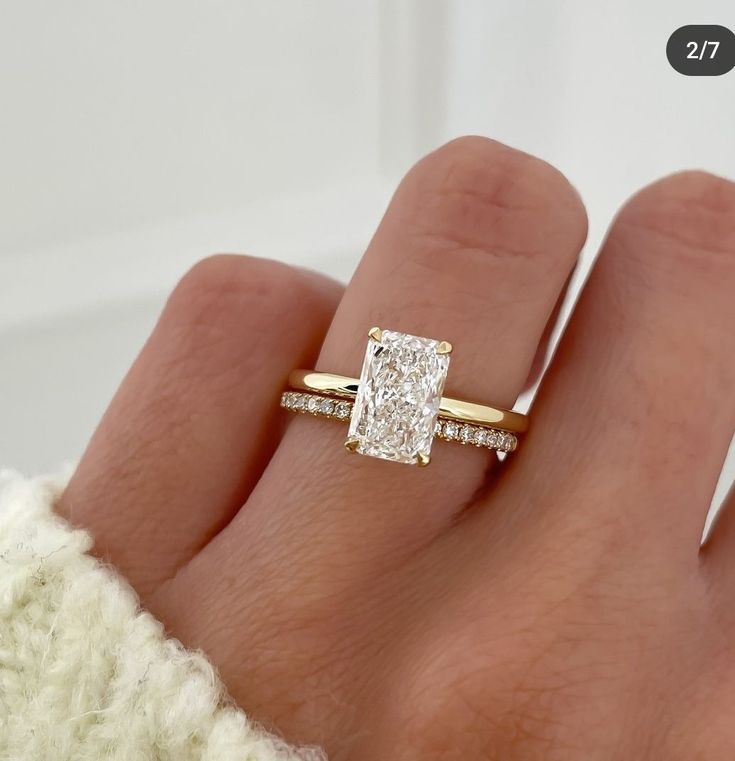 a woman's hand with a diamond ring on top of her finger and an engagement band