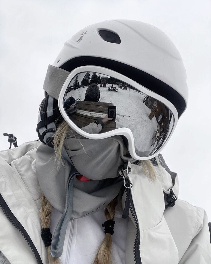 a woman wearing ski goggles and a white jacket