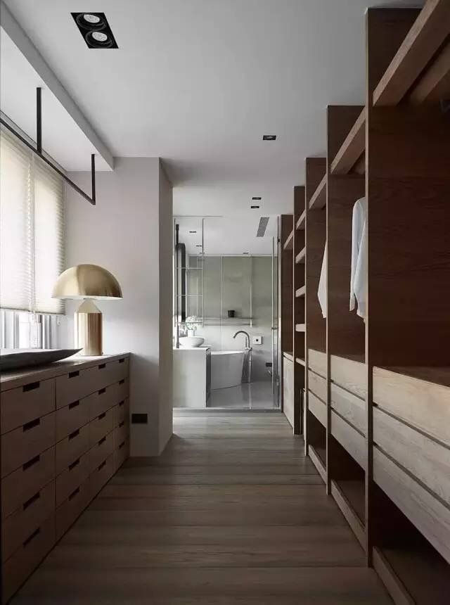 a long narrow bathroom with wooden cabinets and white towels hanging on the wall next to it