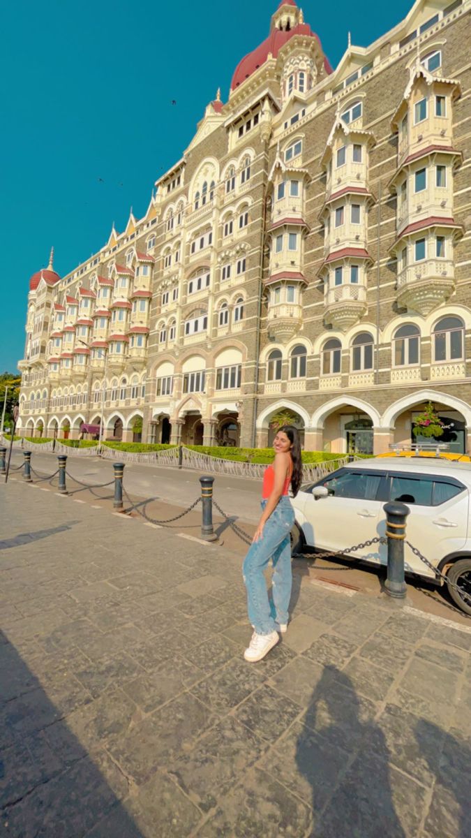 a woman standing next to a white car in front of a large building