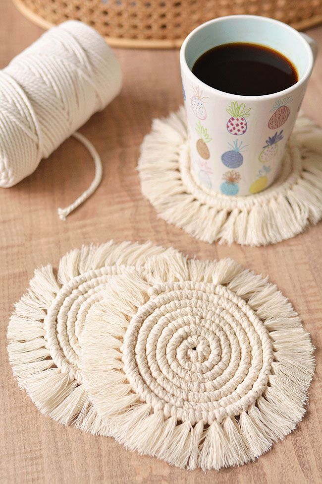 a cup of coffee sitting on top of a wooden table next to yarn and a basket