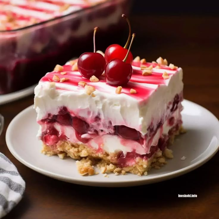 a piece of cake sitting on top of a white plate next to a bowl of cherries