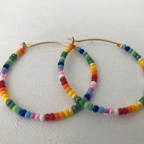 Colorful glass rainbow beads adorn a gold hoop earring. These lightweight earrings are so versatile. Trendy Rainbow Hoop Jewelry, Multicolor Small Hoop Jewelry With Spacer Beads, Trendy Rainbow Round Beads Jewelry, Trendy Rainbow Round Bead Jewelry, Multicolor Small Hoop Earrings For Everyday, Multicolor Hoop Earrings With Ear Wire, Trendy Multicolor Hoop Earrings With Ear Wire, Everyday Multicolor Small Hoop Earrings, Trendy Multicolor Hoop Earrings As Gift