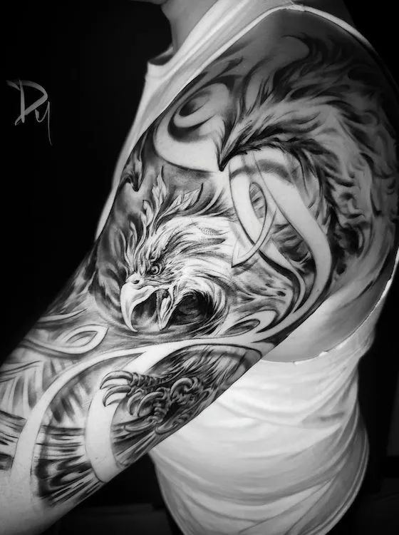 a man's arm with an eagle and wolf tattoo on it, in black and white