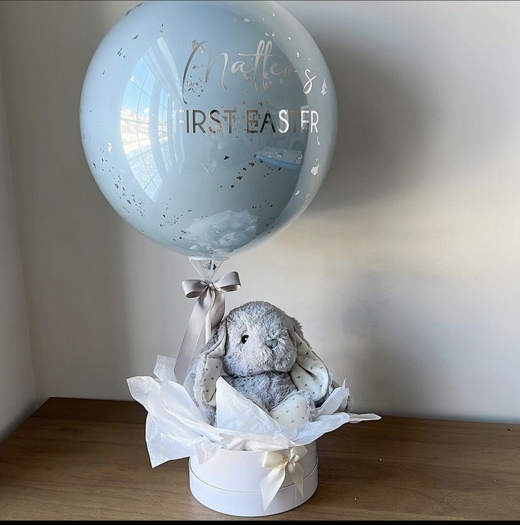 a stuffed animal in a box with a balloon on the table next to it,