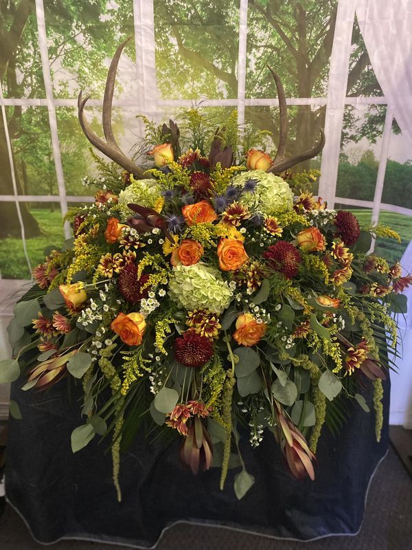 an arrangement of flowers and antlers is displayed in front of a window