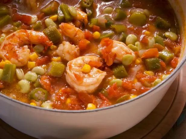 a pot filled with shrimp and vegetables on top of a wooden table