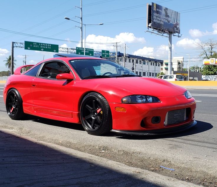 a red sports car is parked on the side of the road in front of an intersection