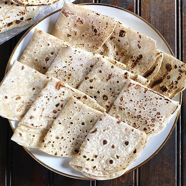 some tortillas are on a white plate and brown table cloth is next to it