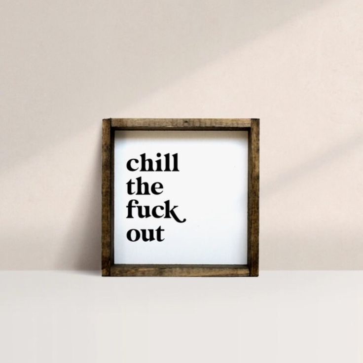 a wooden frame with the words chill the fock out in black ink on it