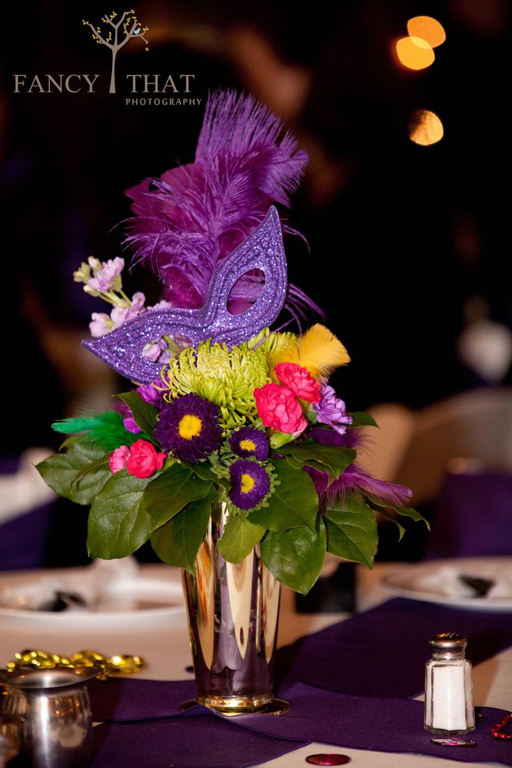 a vase filled with purple and yellow flowers on top of a table covered in confetti