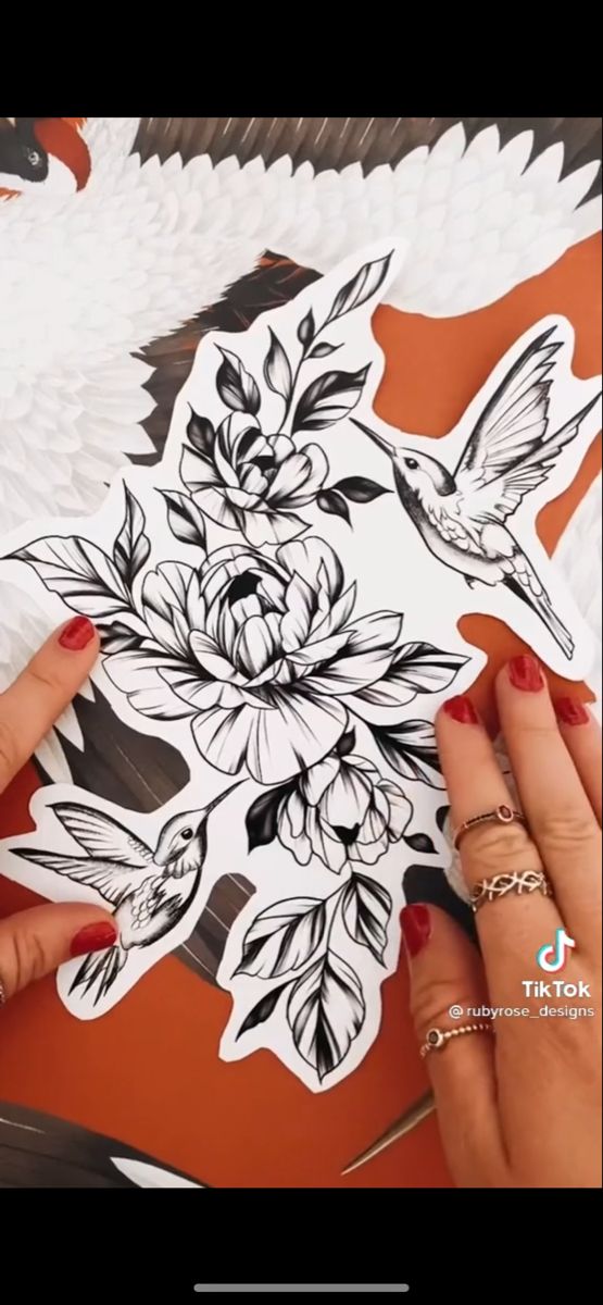 someone is cutting out flowers and birds on a piece of paper that has been drawn