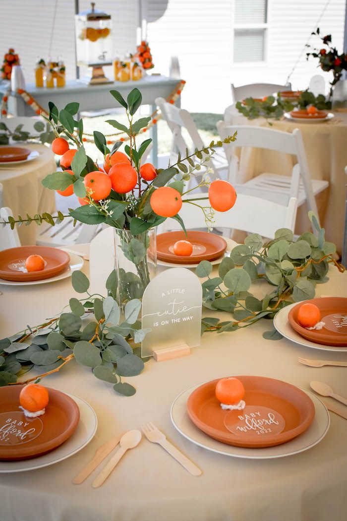 the table is set with orange plates and place settings